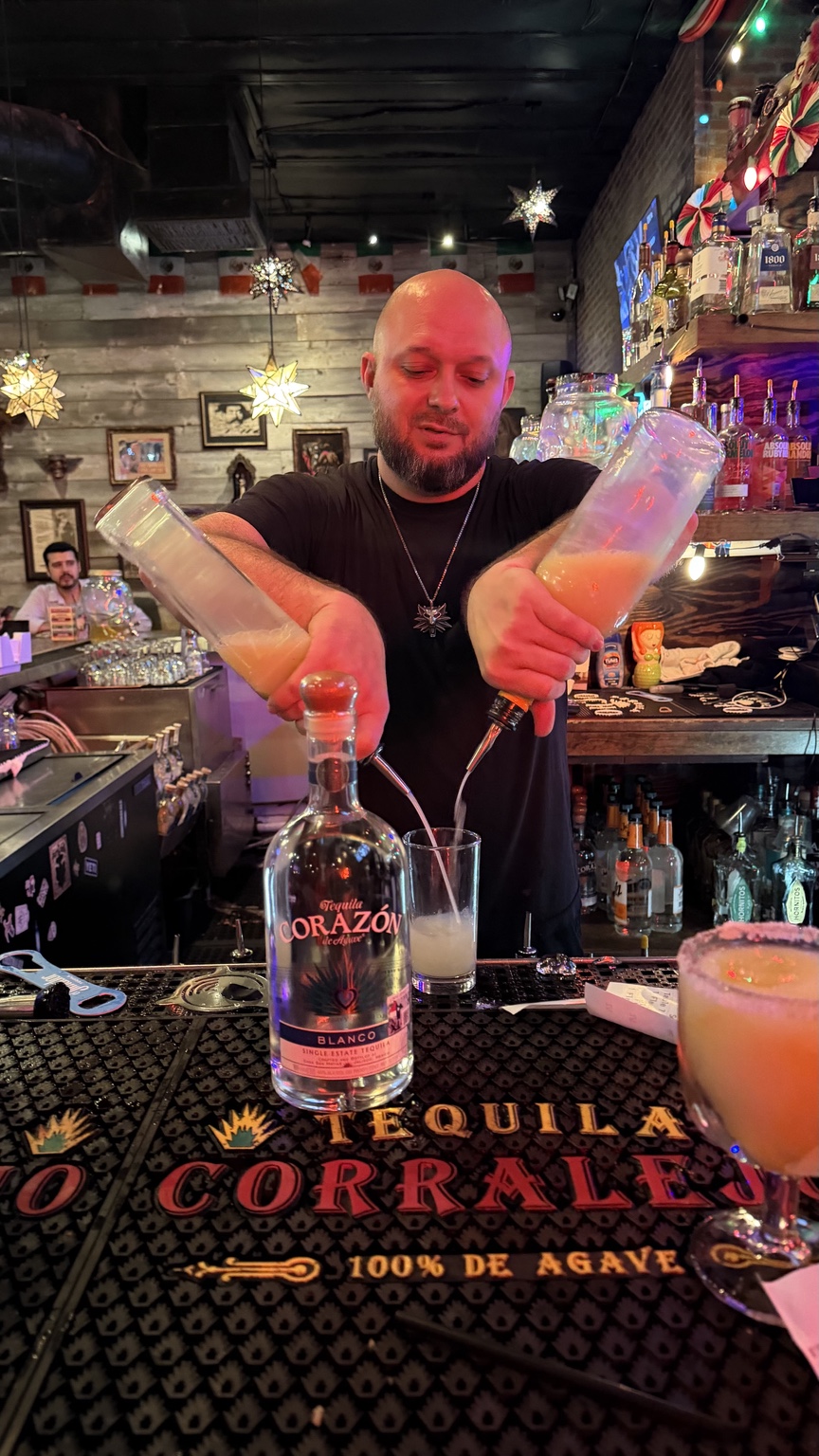 Bartender creating a Corazón Tequila cocktail with a dramatic double pour
